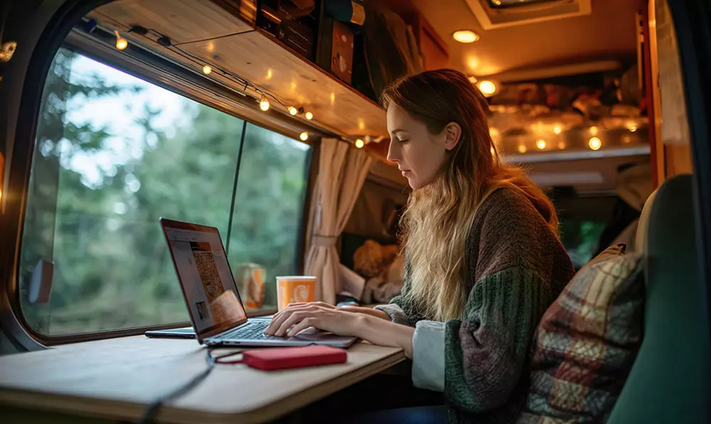 O persoană lucrând la un laptop cu idei creatoare (beculețe, note) în jurul ei.
