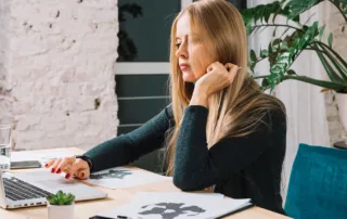 Laptop deschis pe o masă de birou, afișând o pagină web de prezentare profesională, cu secțiuni pentru servicii, blog și contact.