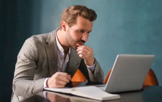 Antreprenor in fata unui laptop alegand numele de domeniu pentru site-ul sau