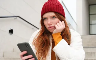 Utilizatoare frustrata asteptand incarcarea lenta a unui site pe telefonul mobil