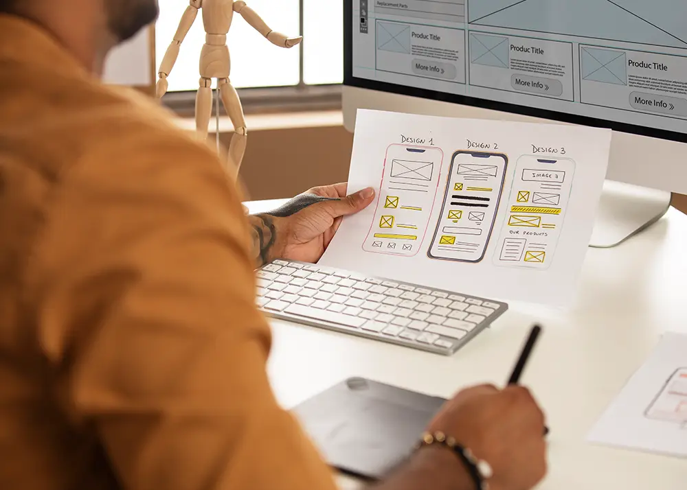 Designer UX care analizează wireframe-uri pentru interfețe mobile, în procesul de creare site web