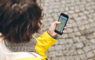 Persoană care caută o afacere locală pe Google Maps de pe telefon, pe o stradă pavată